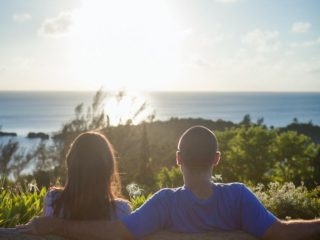 Couple watching a sunset whilst sat on a bench on a Caribbean cruise - Accent On Travel