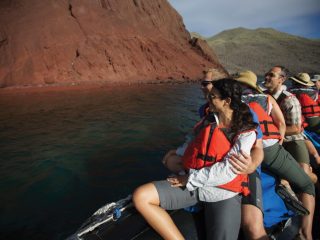 Tourists looking at the red rocks in the Galapagos - Accent On Travel