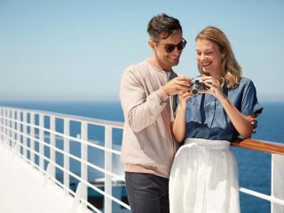 Couple on European cruise looking at a camera on deck - Accent On Travel