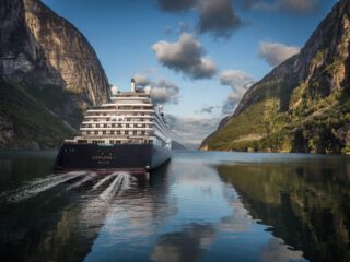 Cruise ship travelling up river in-between two large mountains - Accent on Travel